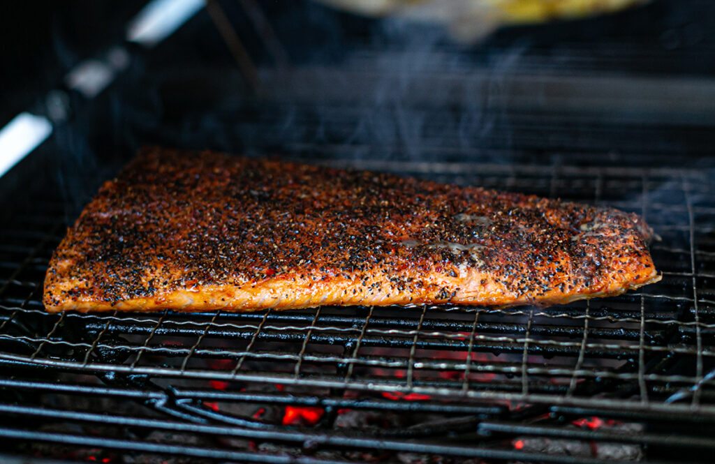 large spice rubbed smoked salmon fillet on a coal bbq grill