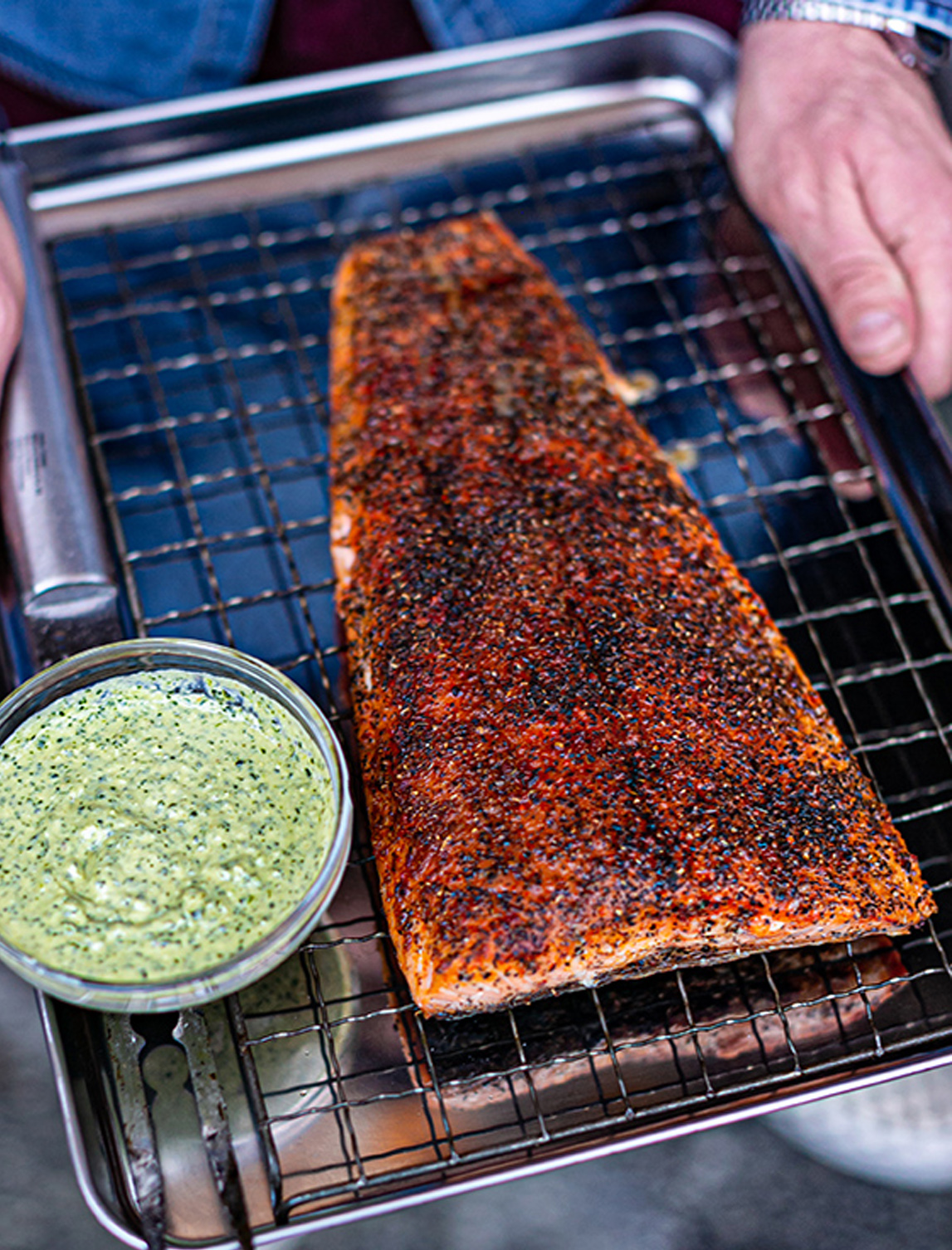 large bbq spice rubbed smoked salmon fillet served on a roasting tray next to a side bowl of Charred Green Feta Sauce
