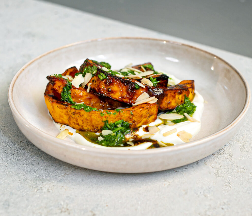 ceramic bowl with yoghurt, oven roasted pumpkin, maple glaze, coriander sauce and toasted almond flakes