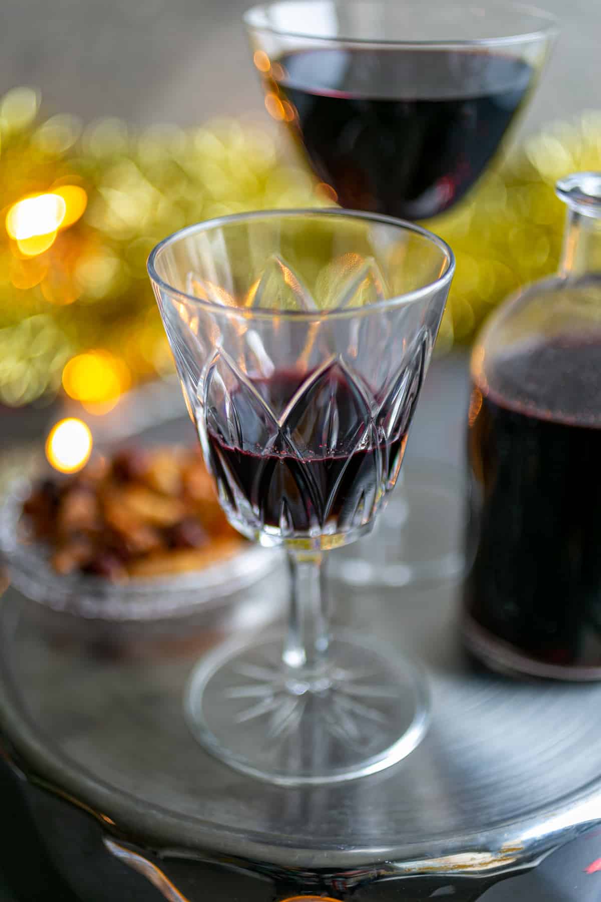 Christmas tinsel and lights surrounding a silver platter of glasses filled with mulled wine