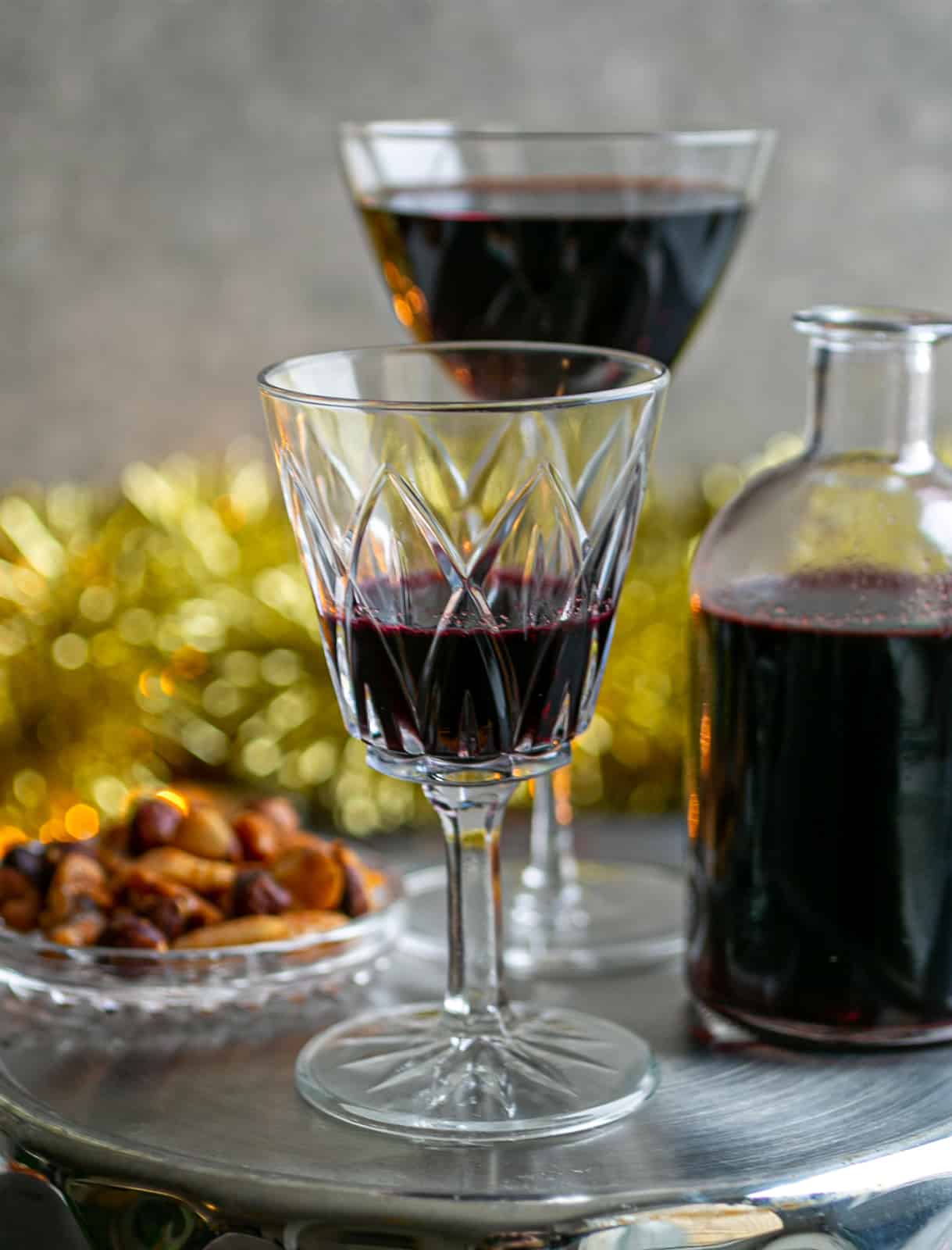 Christmas tinsel and lights surrounding a silver platter of glasses filled with mulled wine