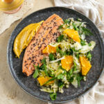 salmon trout with fennel and orange salad on a black plate
