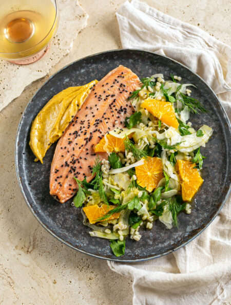 salmon trout with fennel and orange salad on a black plate
