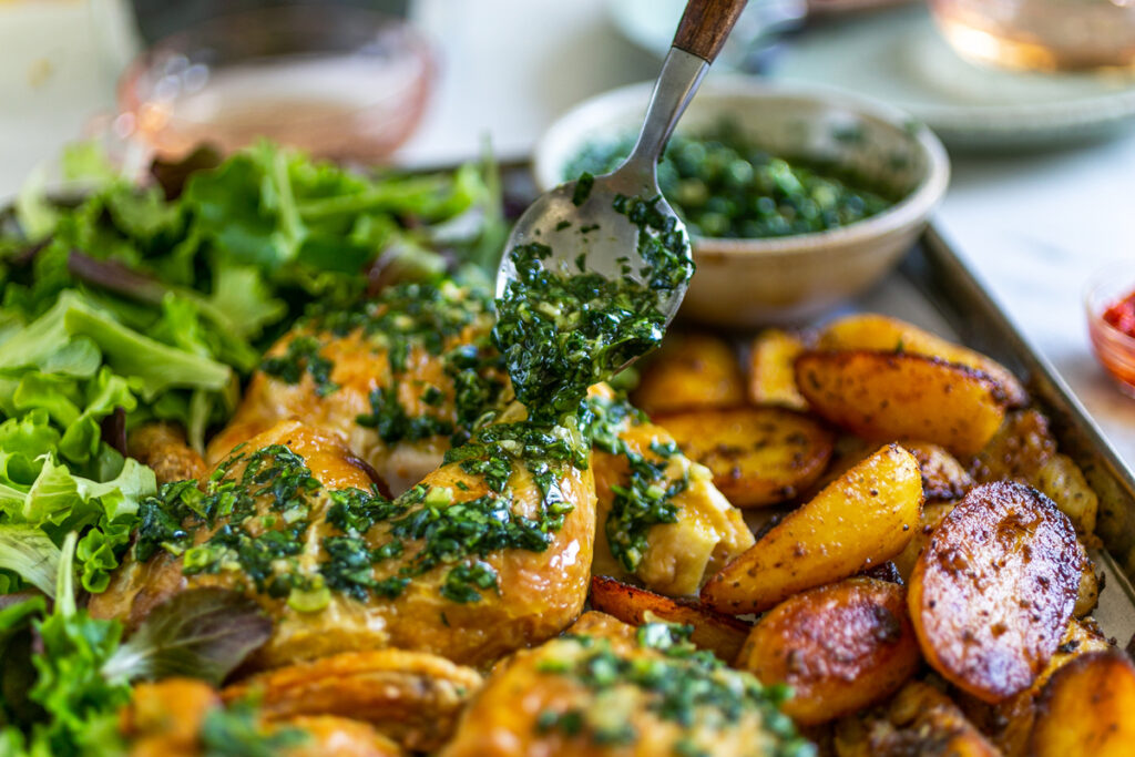close up of oven roasted potatoes and chicken with green herb salsa verde