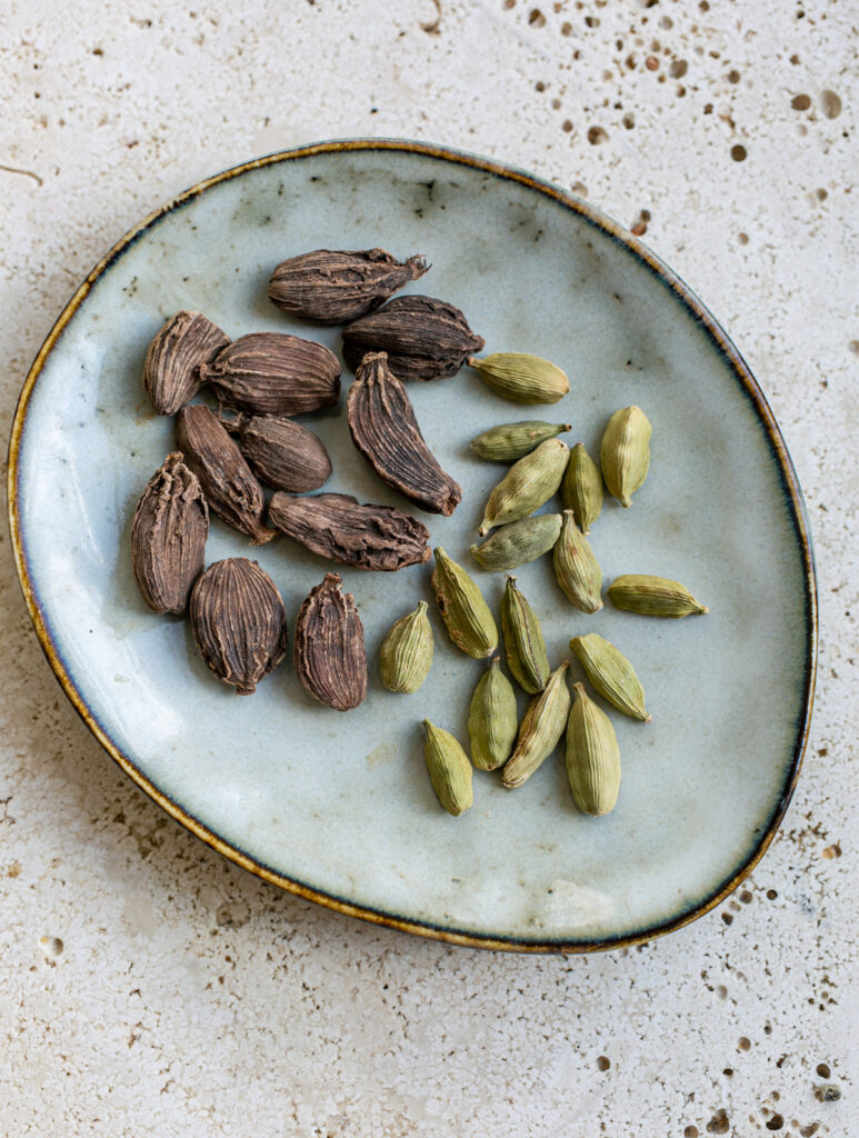 small plate with black cardamom pods and green cardamom pods