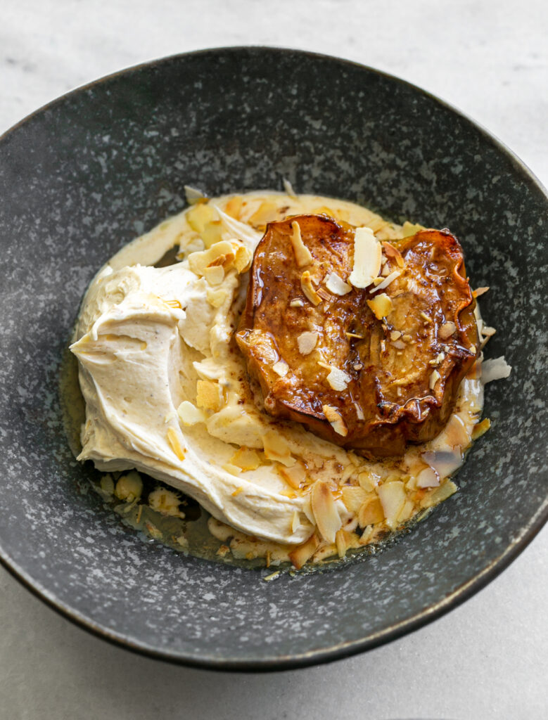 dark ceramic bowls filled with spiced mascarpone and oven roasted apples topped with toasted flaked almonds