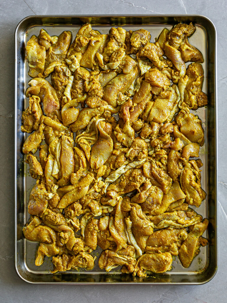 Oven tray with shawarma spice marinated chicken stips ready to be roasted