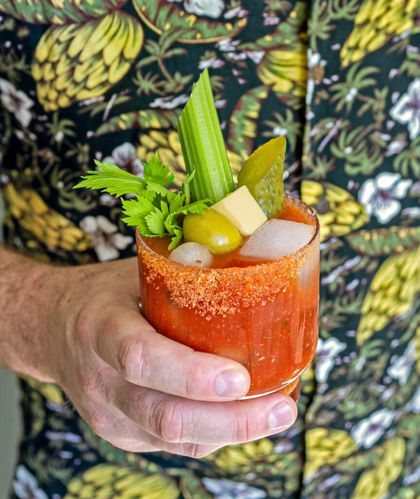 man holding a glass of bloody mary cocktail