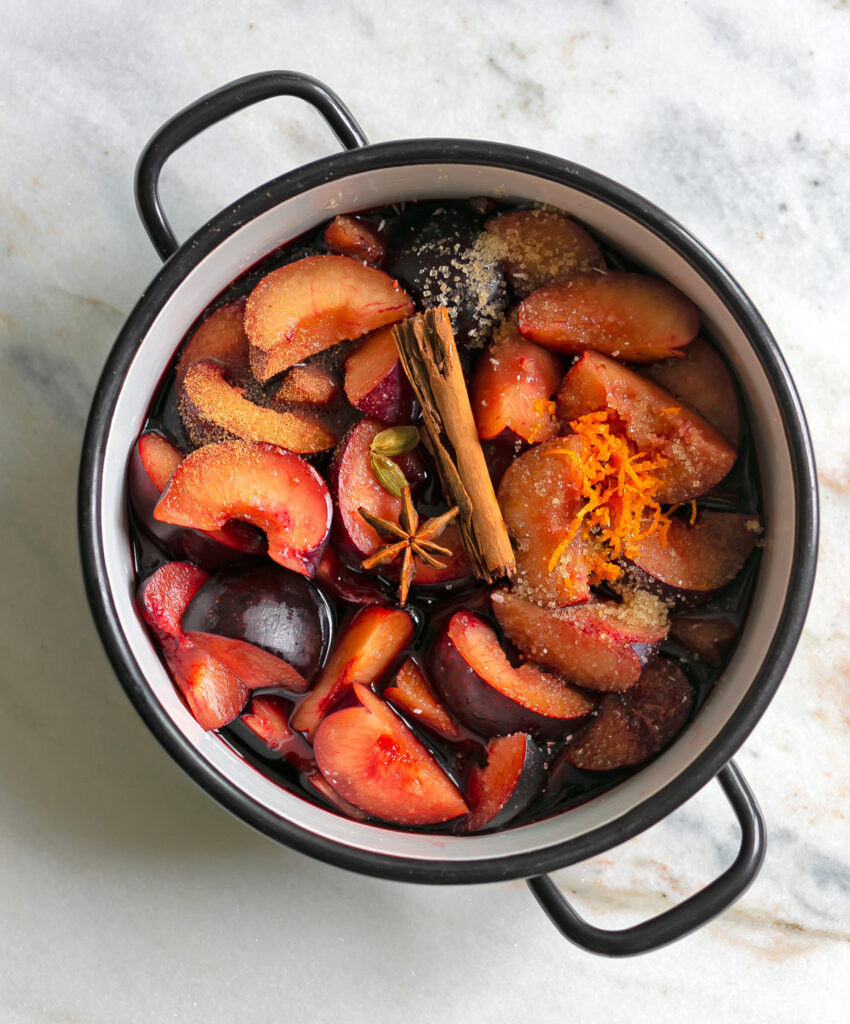 oven pot filled with plums, spices and red wine for fruit compote