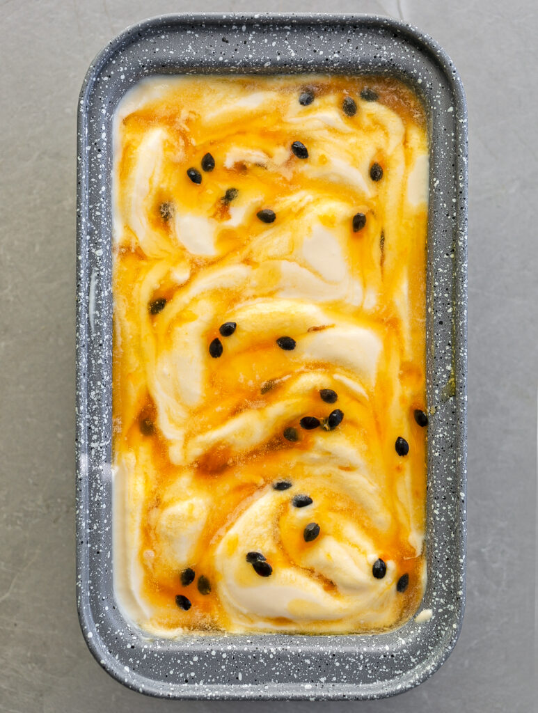 grey freezer container filled with Passion Fruit No Churn Ice Cream