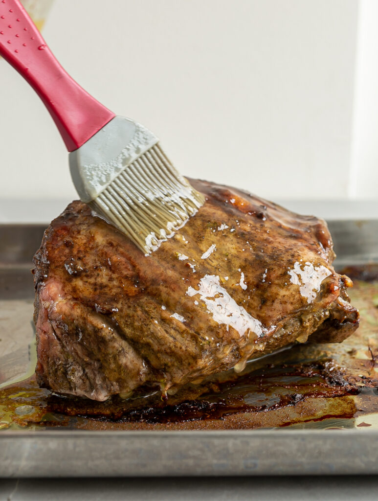 Pork shoulder roast being brushed with a Marmalade Rum glaze