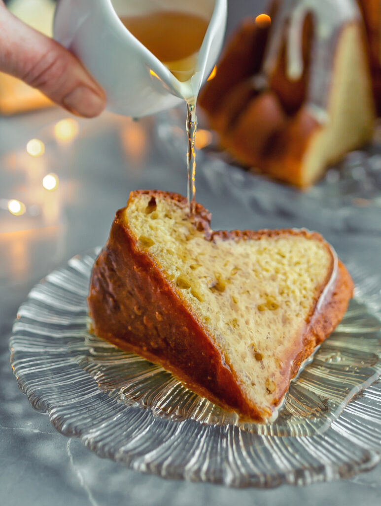 Rum Baba Bundt Cake slice being poured with rum sugar syrup