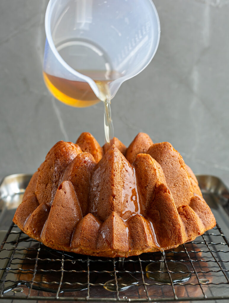 Rum Baba Bundt Cake being poured with a sugar rum syrup